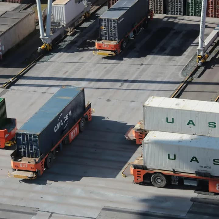Shipping containers and yard tractors at a logistics terminal.
